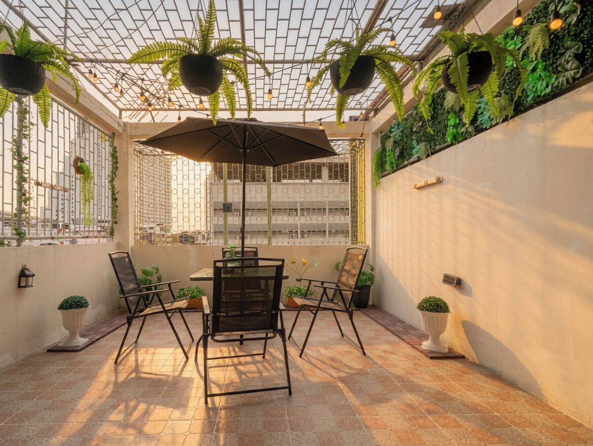 A covered patio with a table and chairs, potted plants, and a view through a glass ceiling.