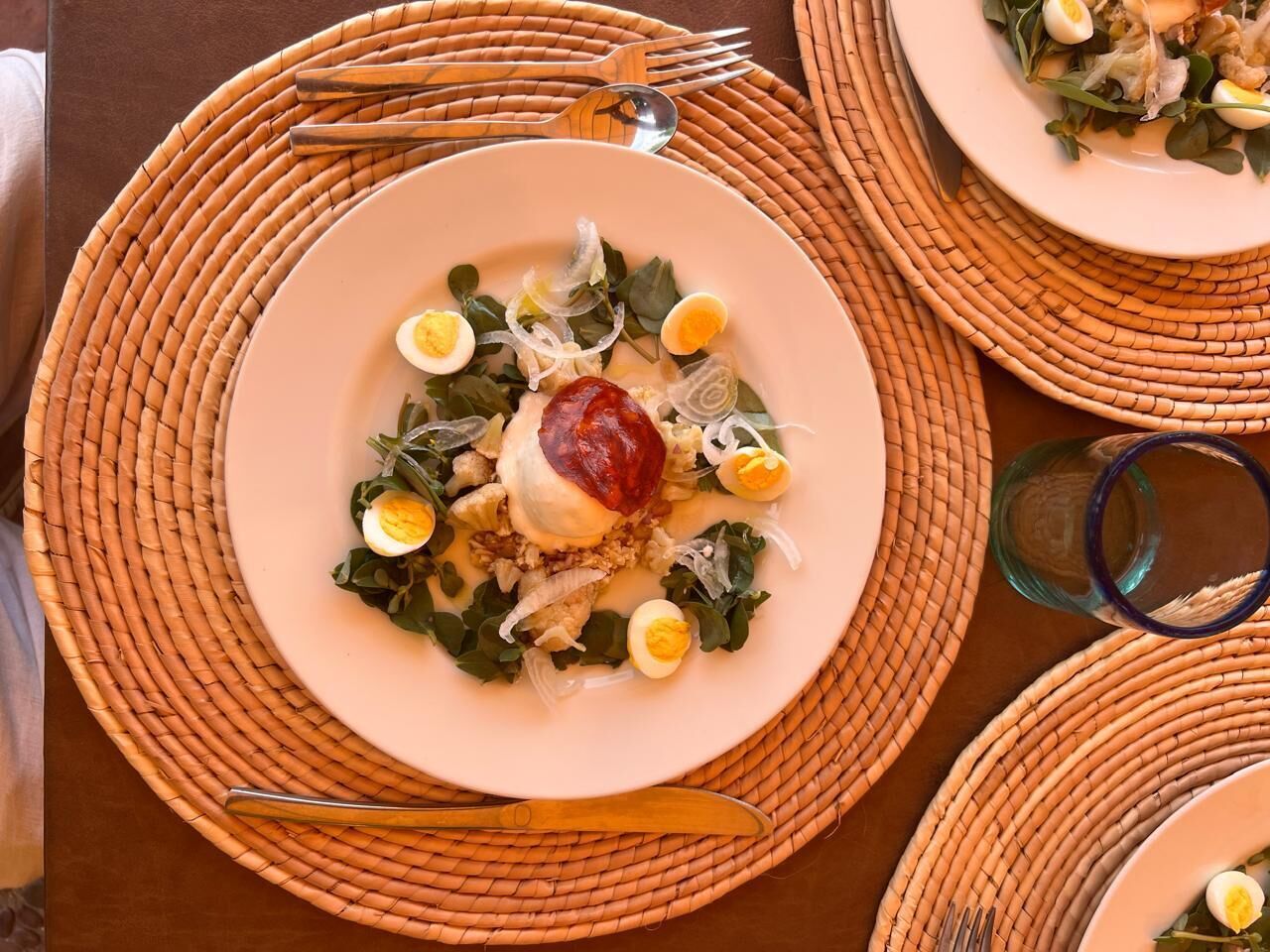 A dining table with a plate of food, a fork, and a spoon.