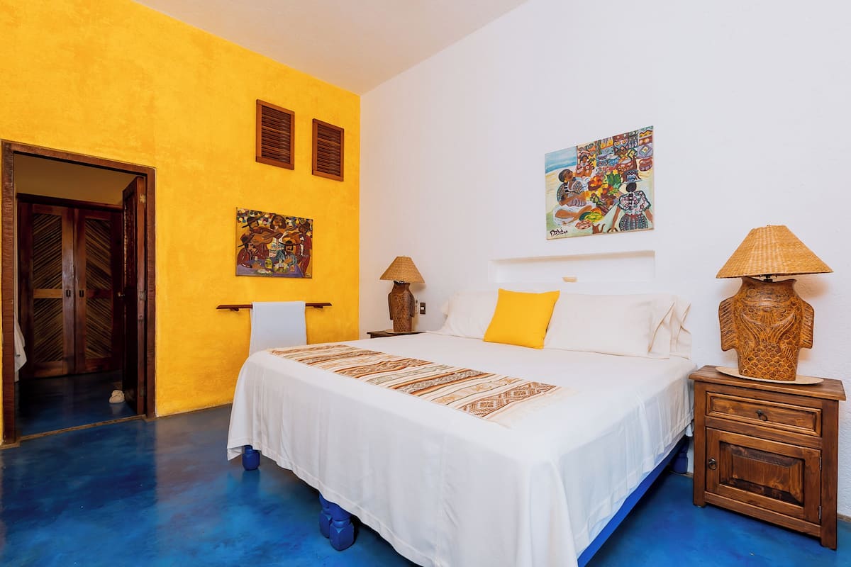 A bedroom with a bed, a nightstand, a lamp, and artwork on the walls.