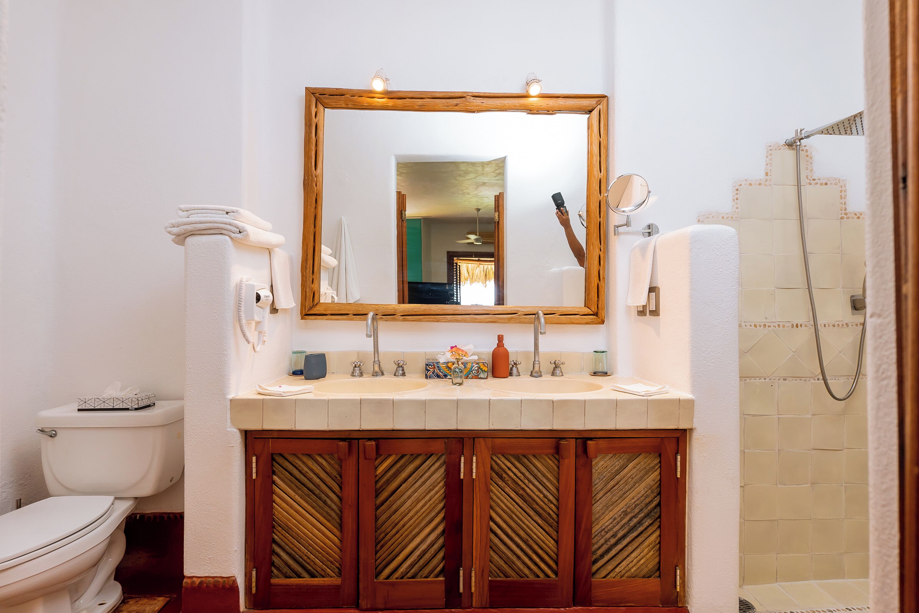 A bathroom with a wooden vanity, a large mirror, a toilet, and a shower area.