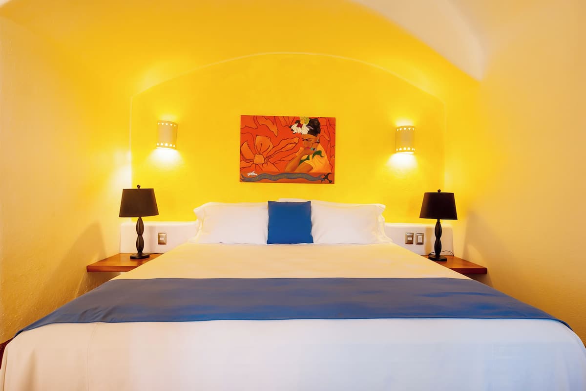 A hotel room with a bed, two bedside lamps, a nightstand, and a wall-mounted painting.