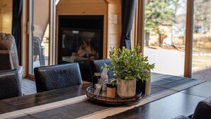 Een eetgedeelte met een houten tafel, stoelen, een potplant en een open haard.