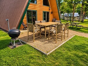 A wooden deck with a table and chairs, a barbecue grill, and a picnic table.