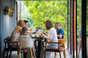 A family dining at a table with a view of trees through large windows. - YesHue Eco Waterfall Retreat (Hue)