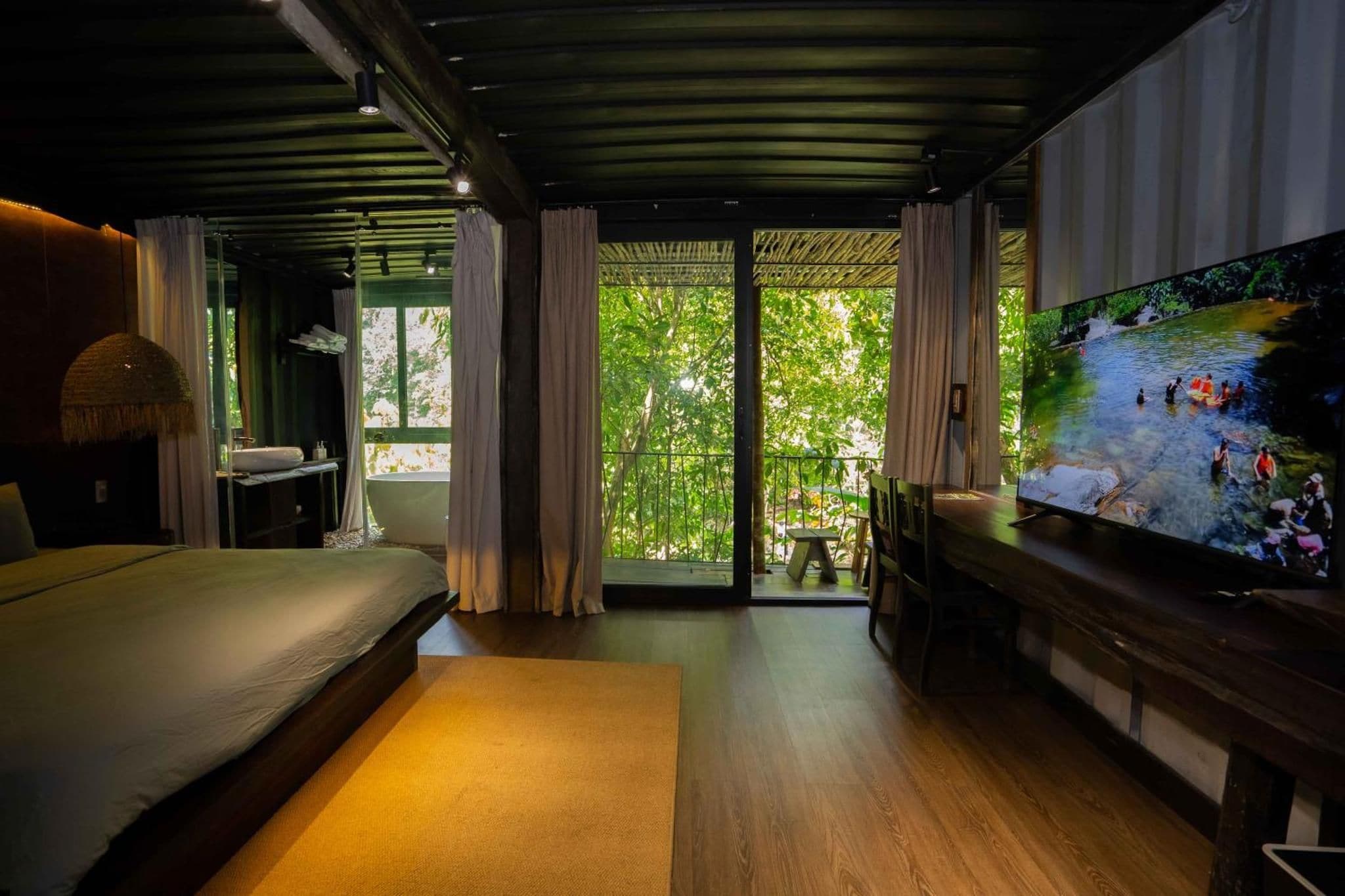 A bedroom with a large bed, a television, and a view of a river outside.