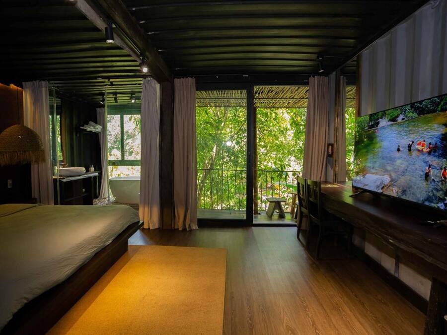 A bedroom with a large bed, a television, and a view of a river outside.