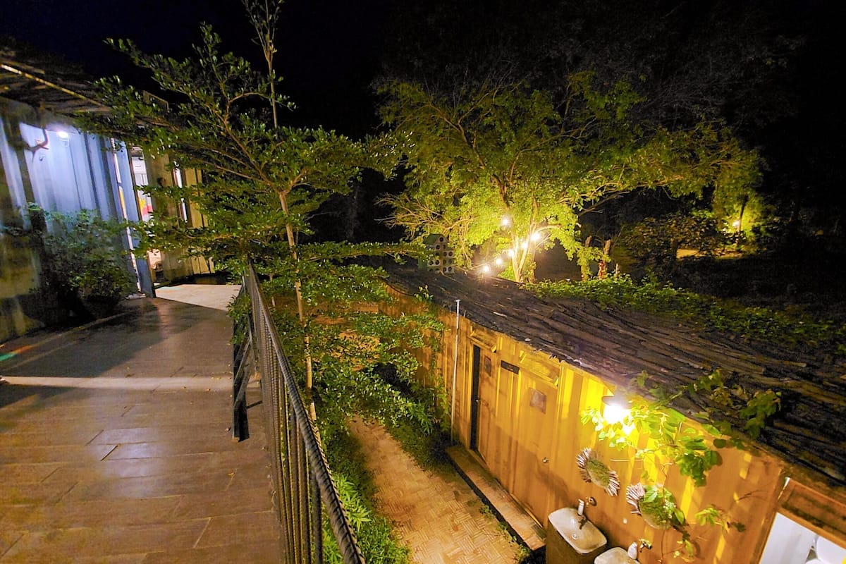 A nighttime outdoor area with a wooden fence, a pathway, and two sinks.