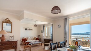 A dining area with a table set for two, a sofa, and a view of the sea.