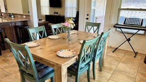 A dining area with a wooden table, green chairs, and a keyboard on a stand. - Beautiful Cozy Edmond Home - 4bed 2bath (Edmond)