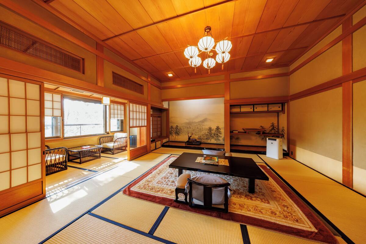 A traditional Japanese room with tatami flooring, a low table, and a hanging lantern.