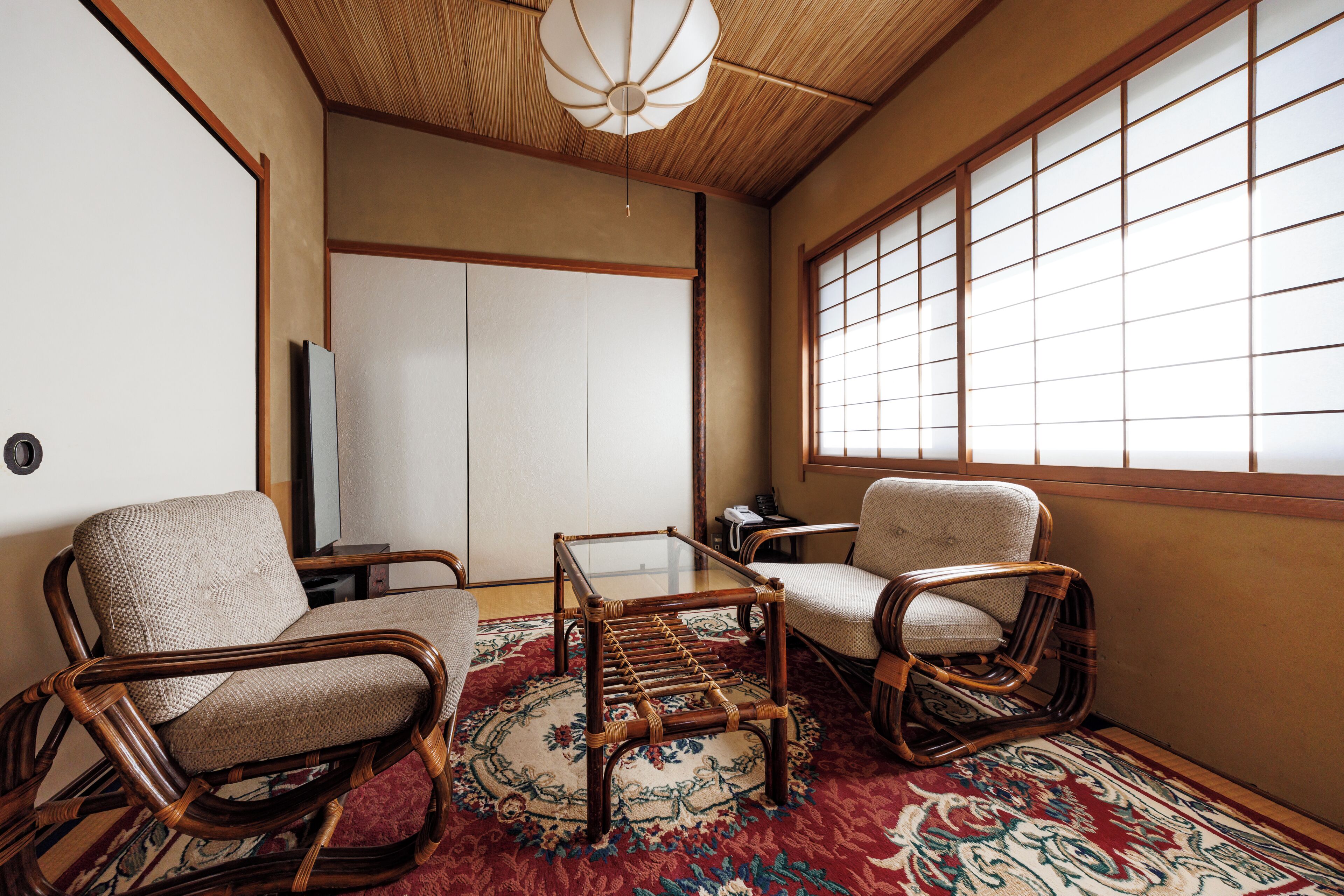 A traditional Japanese room with tatami flooring, a low table, and two tatami mat chairs.
