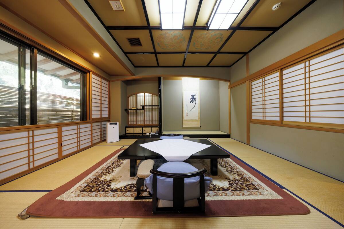 A traditional Japanese room with tatami flooring, a low table with a cushion, and sliding doors.