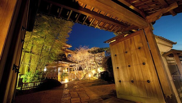 A traditional wooden gate leading to a pathway with a tiled roof overhead. - Shikitei (Nara)