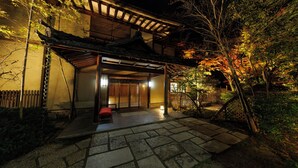 A traditional Japanese house with a wooden exterior, a tiled entrance, and a red bench outside. - Shikitei (Nara)