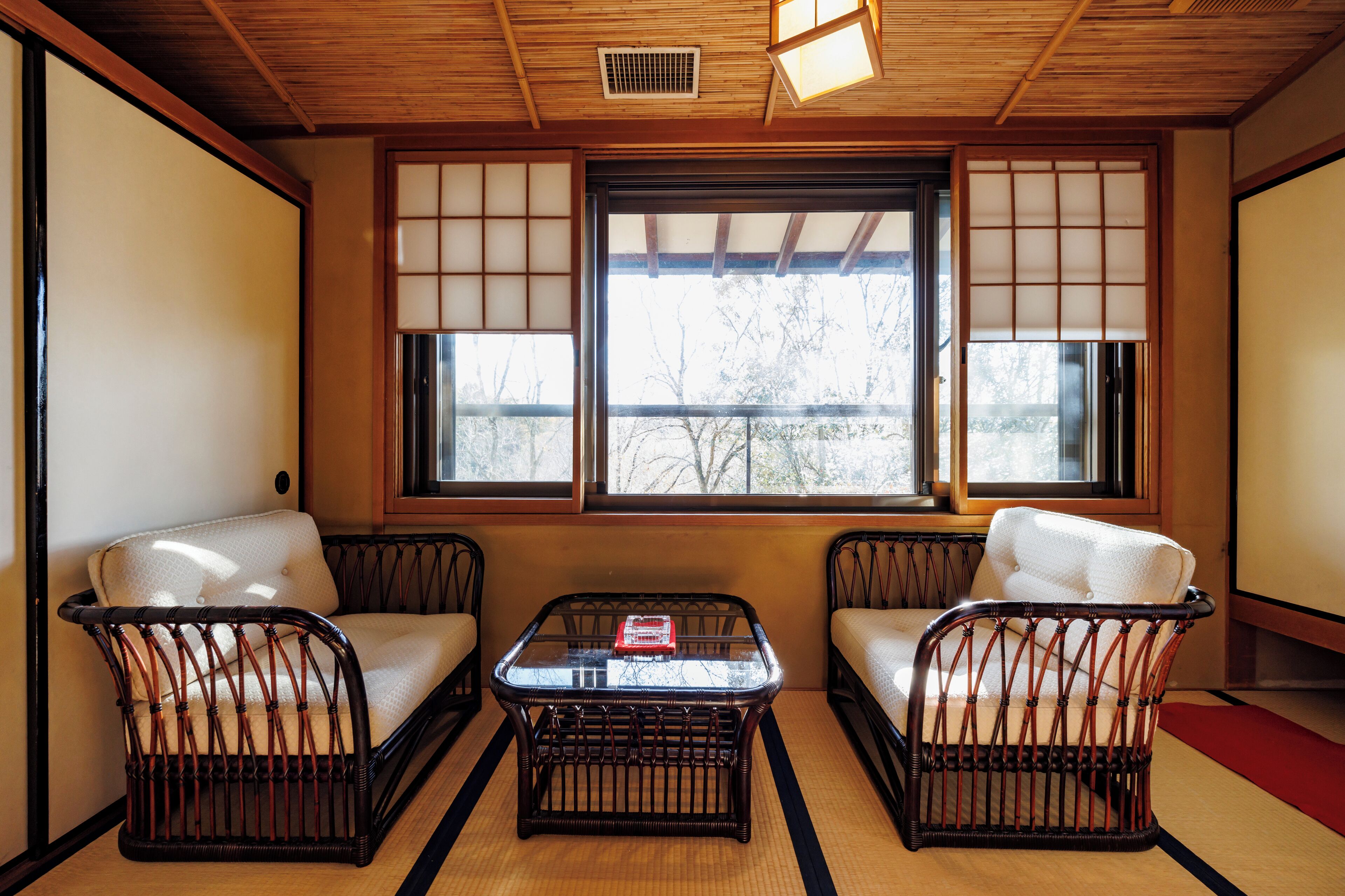 A traditional Japanese-style room with tatami flooring, a low wooden ceiling, and sliding shoji screens.