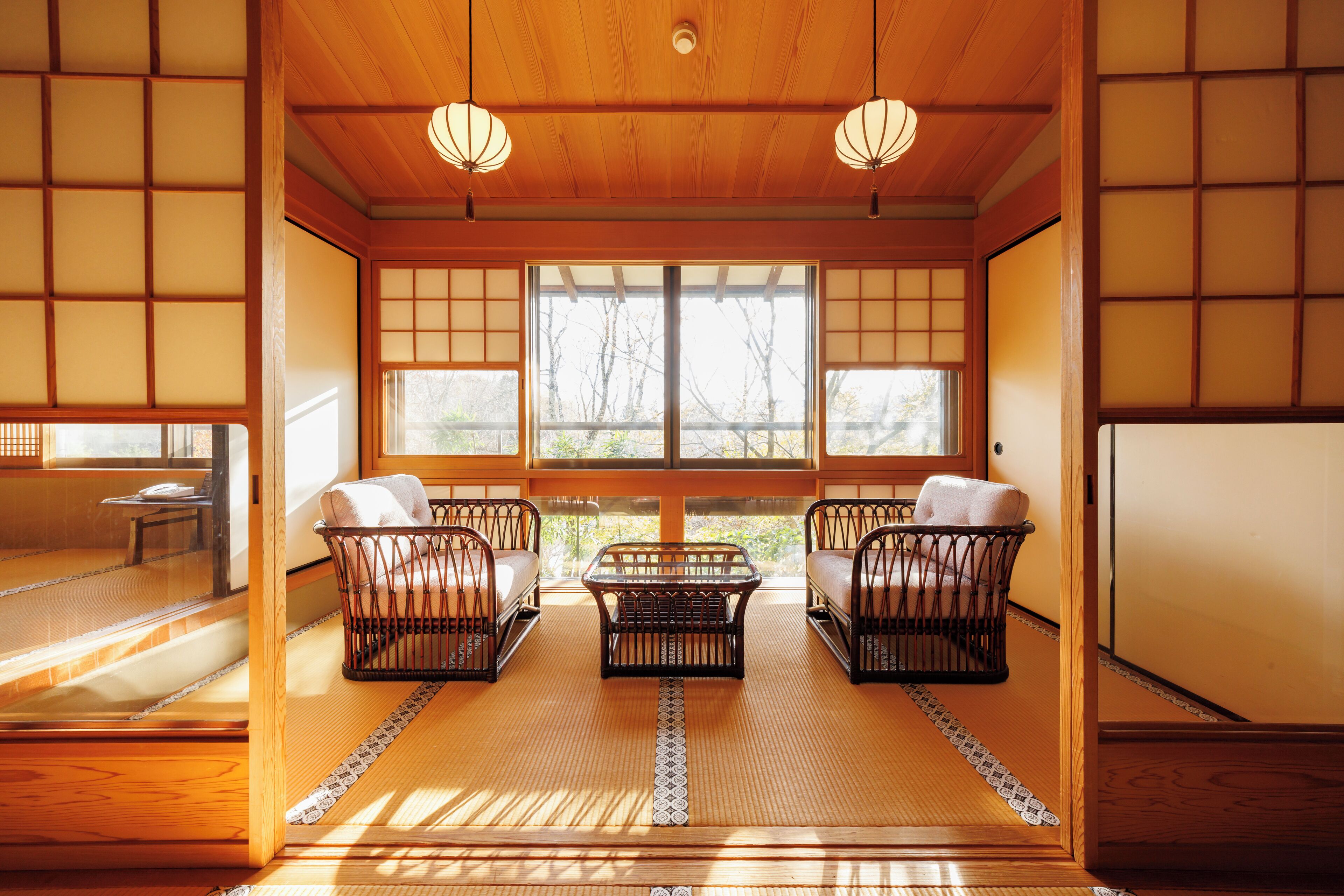 A traditional Japanese room with tatami flooring, sliding doors, and a low table with cushions.