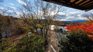 A view from a covered area overlooking a road with trees and a body of water in the distance.