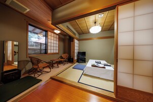 Una habitación japonesa tradicional con suelo de tatami, un futón, una mesita baja con una bandeja y puertas correderas.