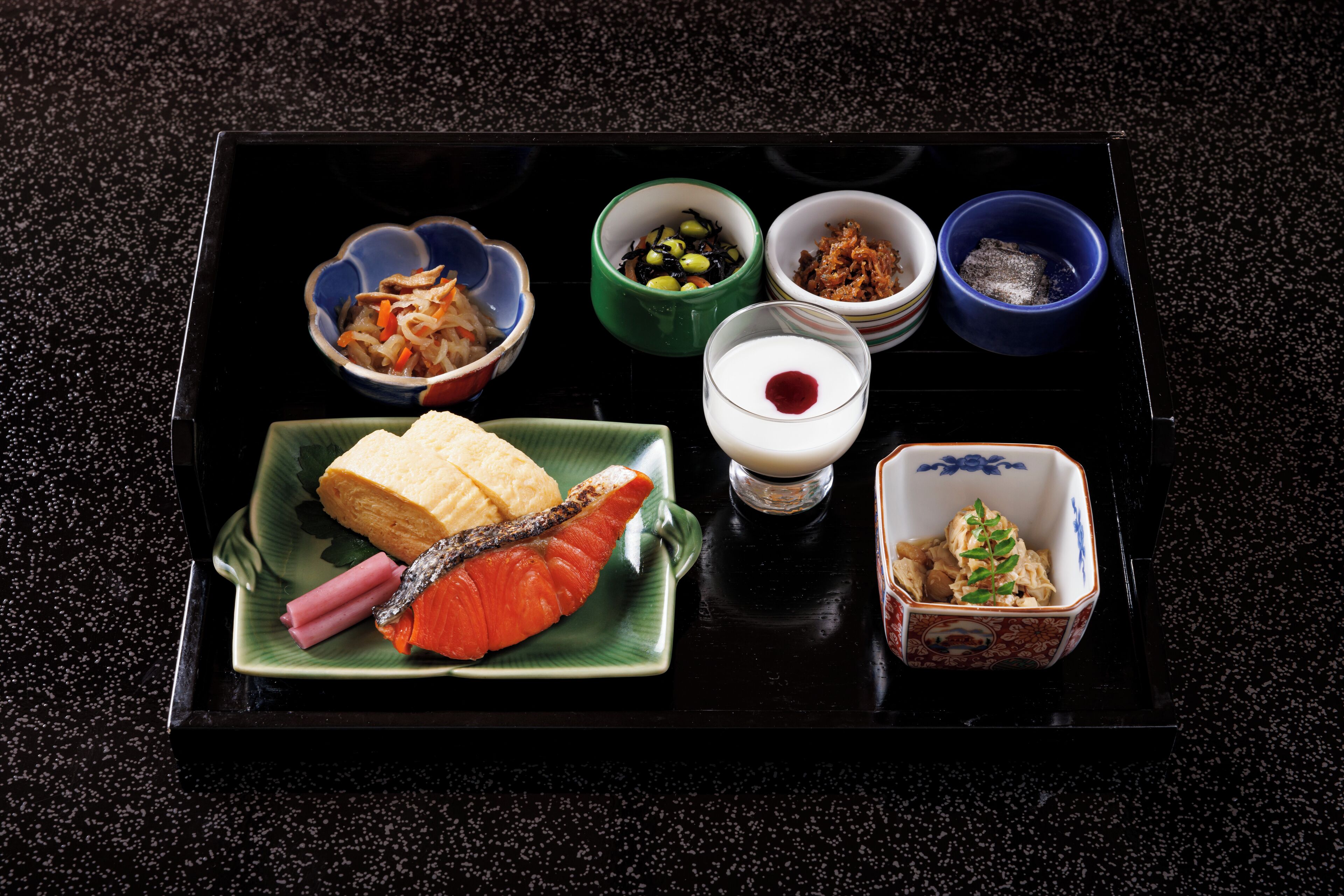 A tray with various food items including a fish, vegetables, and a bowl of soup.