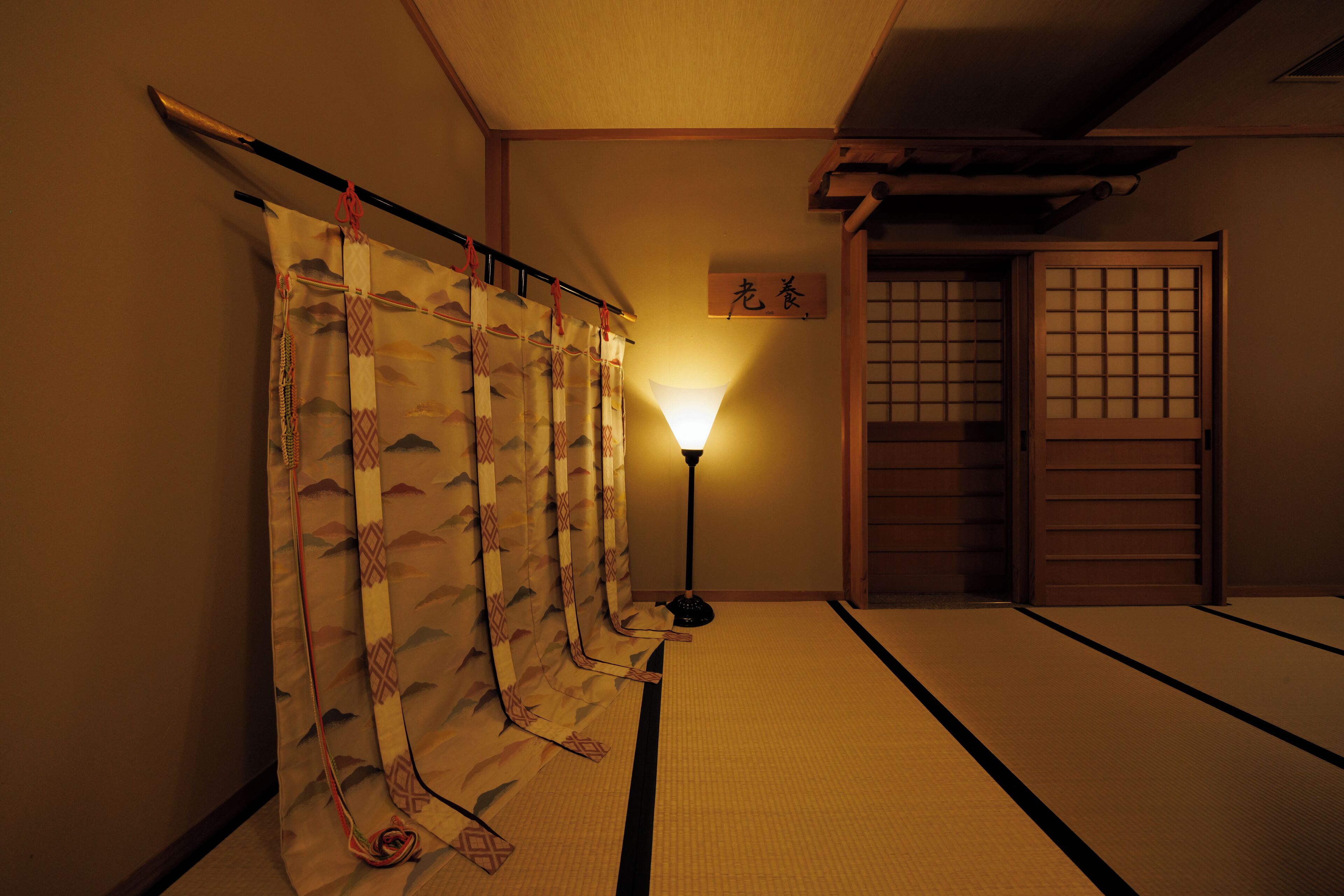 Ein traditioneller japanischer Raum mit Tatami-Böden, Shoji-Bildschirmen und einer hängenden Shoji-Tür.