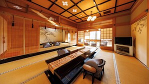 A traditional Japanese room with tatami flooring, a low table, chairs, a television, and sliding doors. - Shikitei (Nara)