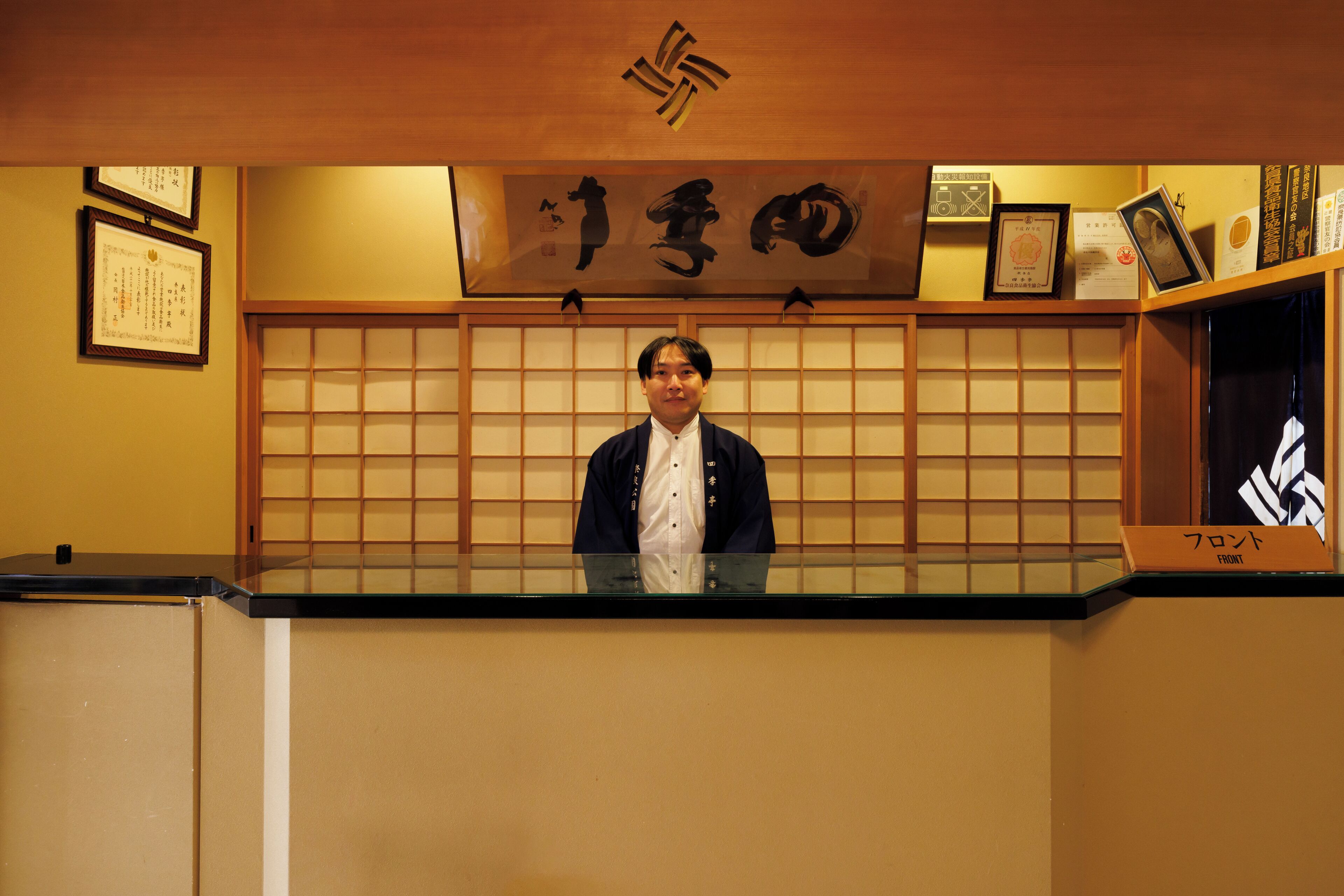 A reception area with a wooden counter, framed certificates, and a large calligraphy piece on the wall.