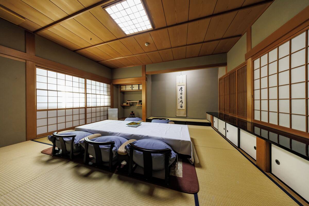 A traditional Japanese room with tatami flooring, a low table with cushions, and sliding doors.