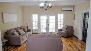 A living room with a beige sofa set, a round coffee table, and a chandelier. - North Ritz Villa (Ocho Rios, Draxhall, St. Ann)
