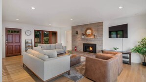 Ein modernes Wohnzimmer mit Kamin, einer Couch, einem Couchtisch und einem an der Wand montierten Fernseher.