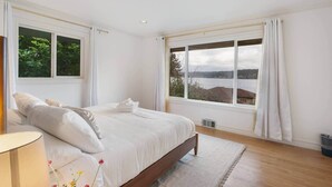 Ein Schlafzimmer mit einem großen Bett, einem Fenster mit Seeblick und einer Heizung.