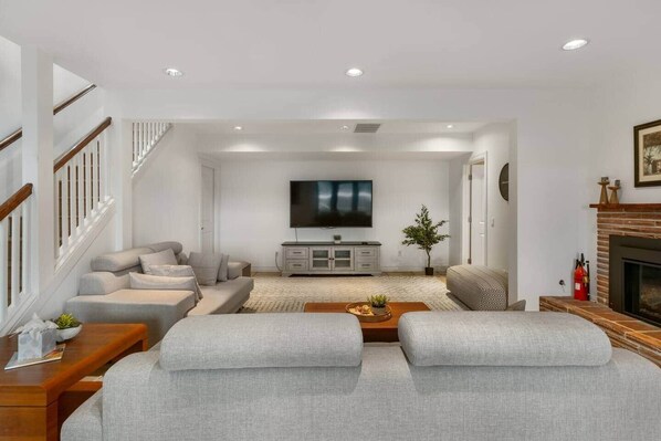 A modern living room with a sofa set, a TV, and a fireplace. - Bellevue Lakeview house (Bellevue)