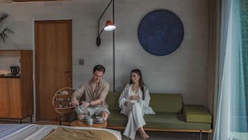 Quarto com uma cama, um sofá verde, um armário de madeira e um objeto decorativo redondo na parede.