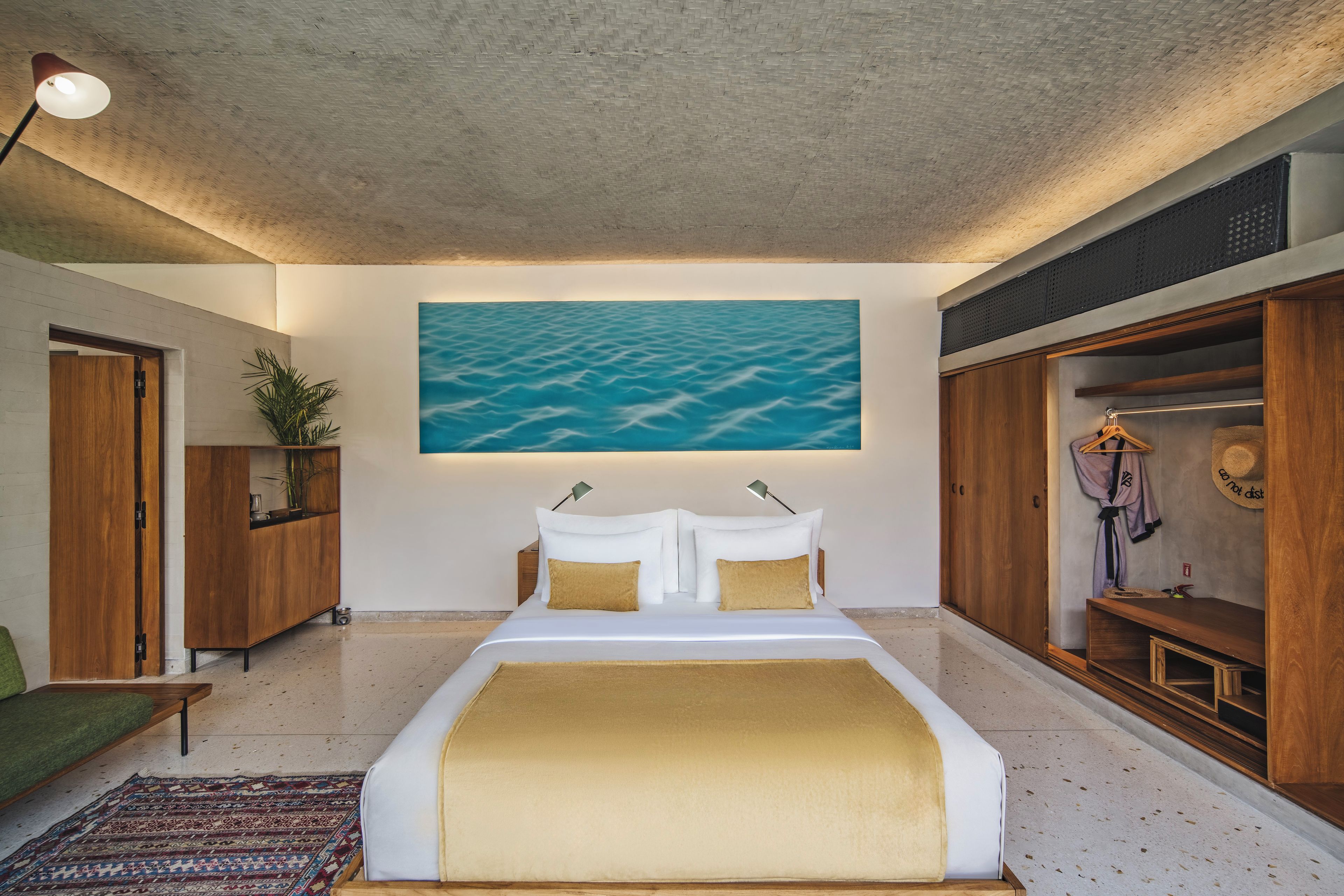 A bedroom with a large bed, a wall-mounted painting, and a wardrobe.