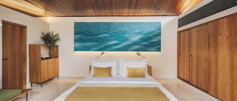 A modern bedroom with a wooden ceiling, a large bed with white bedding, a painting of water on the wall, and a green rug.
