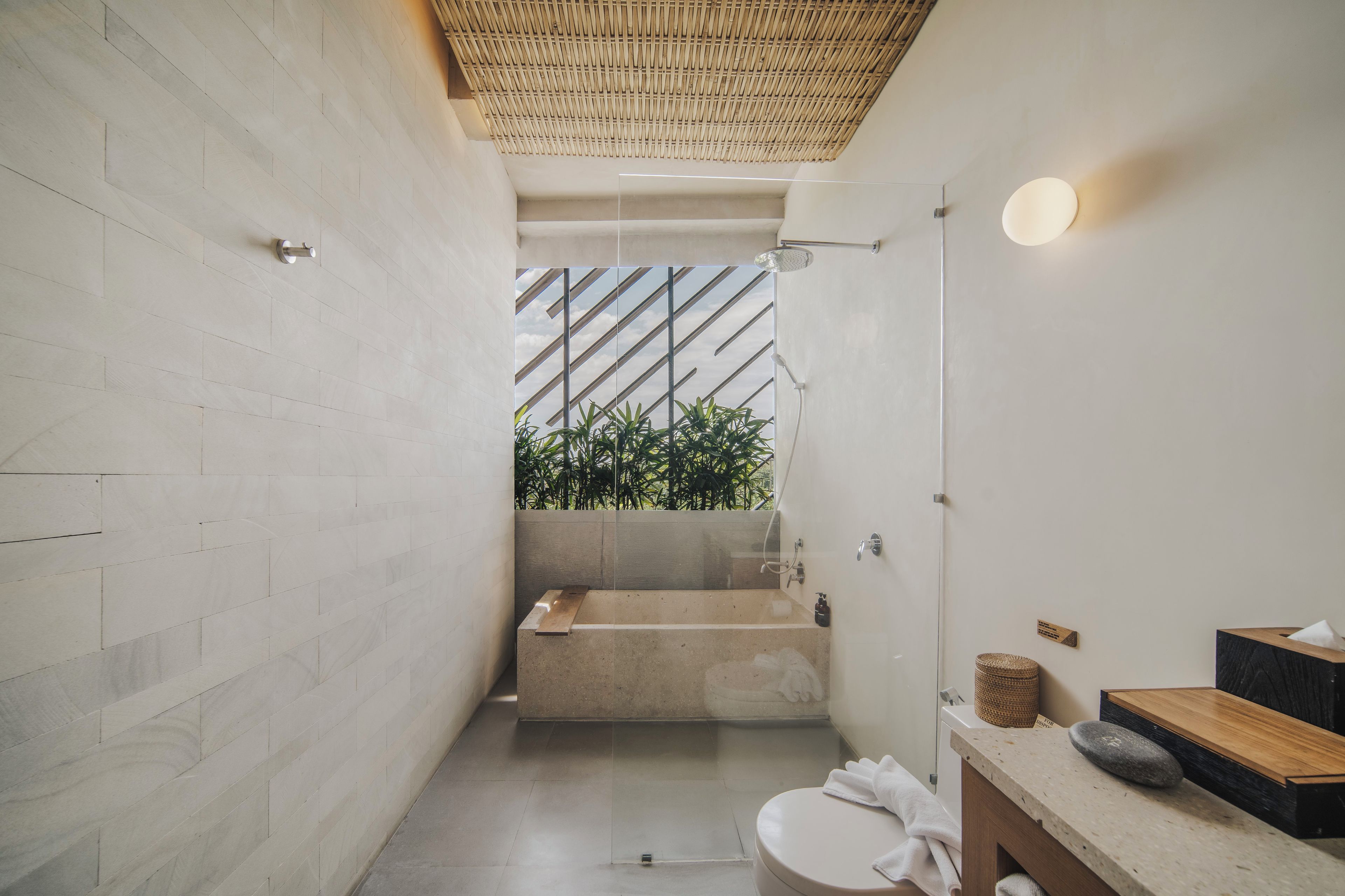 Um banheiro moderno com box de vidro, banheira e vaso sanitário.