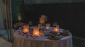 An outdoor dining table set with candles, glasses, and plates of food.
