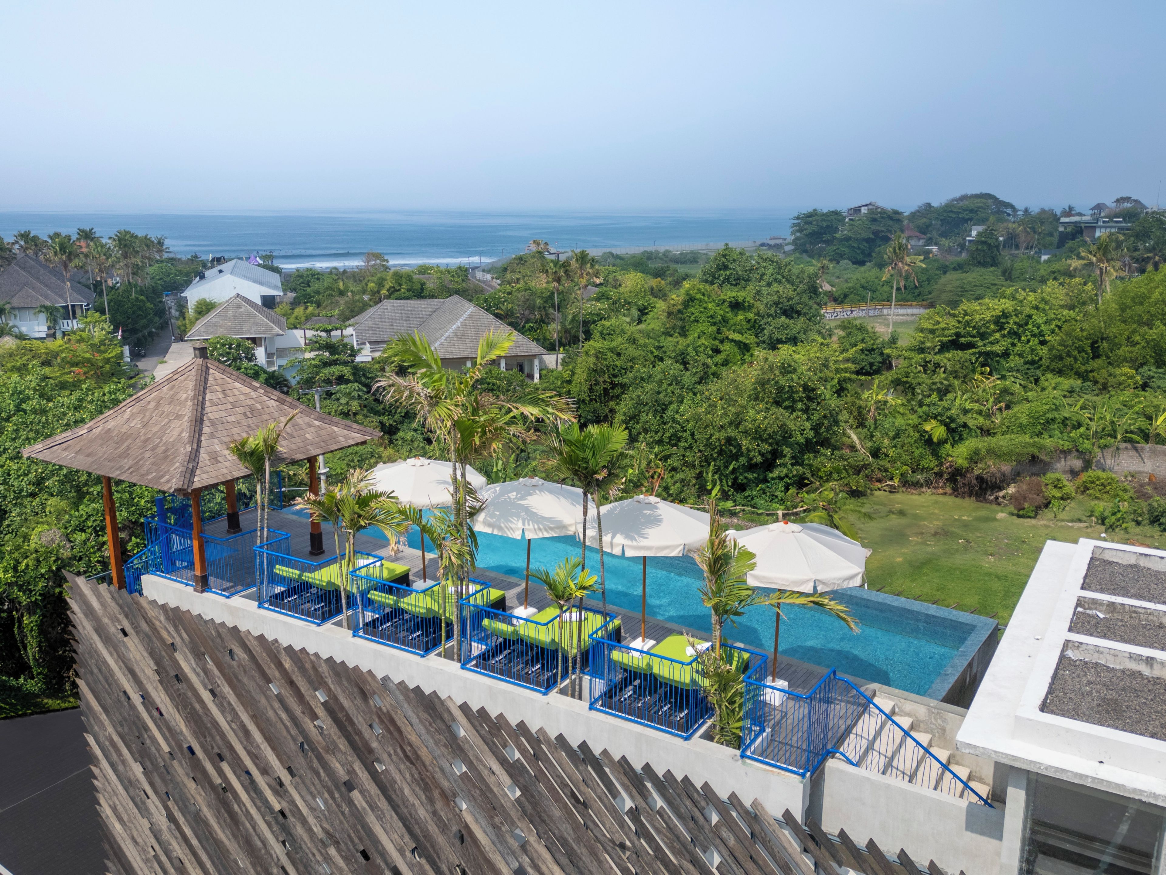 A resort with a pool area, lounge chairs, and a view of the ocean.