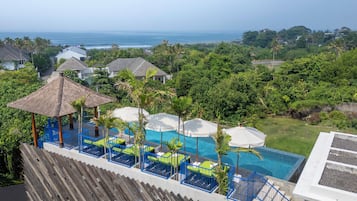 A resort with a pool area, lounge chairs, and a view of the ocean.