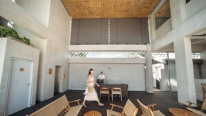 A spacious lobby with a reception desk, seating area, and a staircase leading to upper floors.