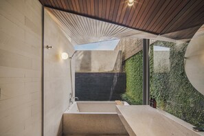 Un interior moderno con una escalera de hormigón, techo de madera y vistas al exterior con vegetación.
