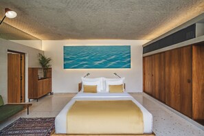 A bedroom with a large bed, a painting of a beach, wooden furniture, and a view of the sea. - Atap Beach Resort Canggu by Ini Vie Hospitality (Pererenan)
