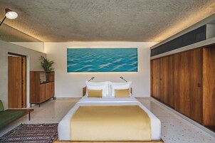 Un dormitorio con una cama grande, un cuadro de playa, muebles de madera y vista al mar.