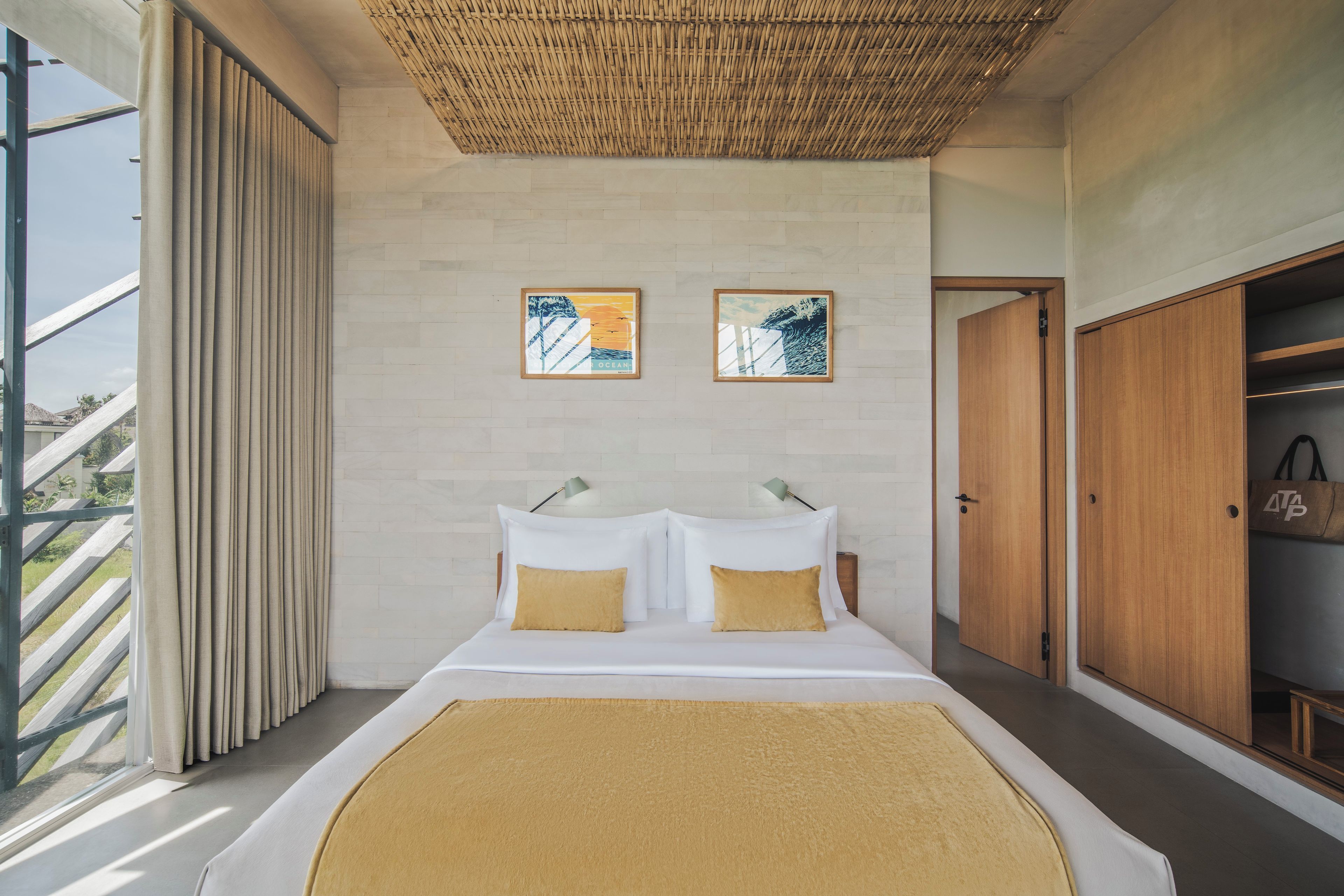 A modern bedroom with a large bed, two pillows, a headboard, a wardrobe, and a wall-mounted artwork.