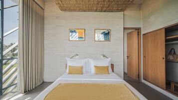 A modern bedroom with a large bed, two pillows, a headboard, a wardrobe, and a wall-mounted artwork.
