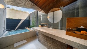Une salle de bain moderne avec une grande baignoire, un meuble-lavabo en bois et un grand miroir.