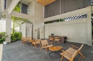 A spacious indoor area with a reception desk, multiple seating arrangements, and a staircase leading to an upper level.