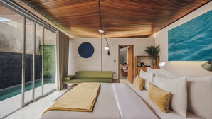 Une chambre d’hôtel moderne avec un grand lit, un canapé vert, une petite table, une œuvre d’art circulaire accrochée au mur et une vue sur une piscine.