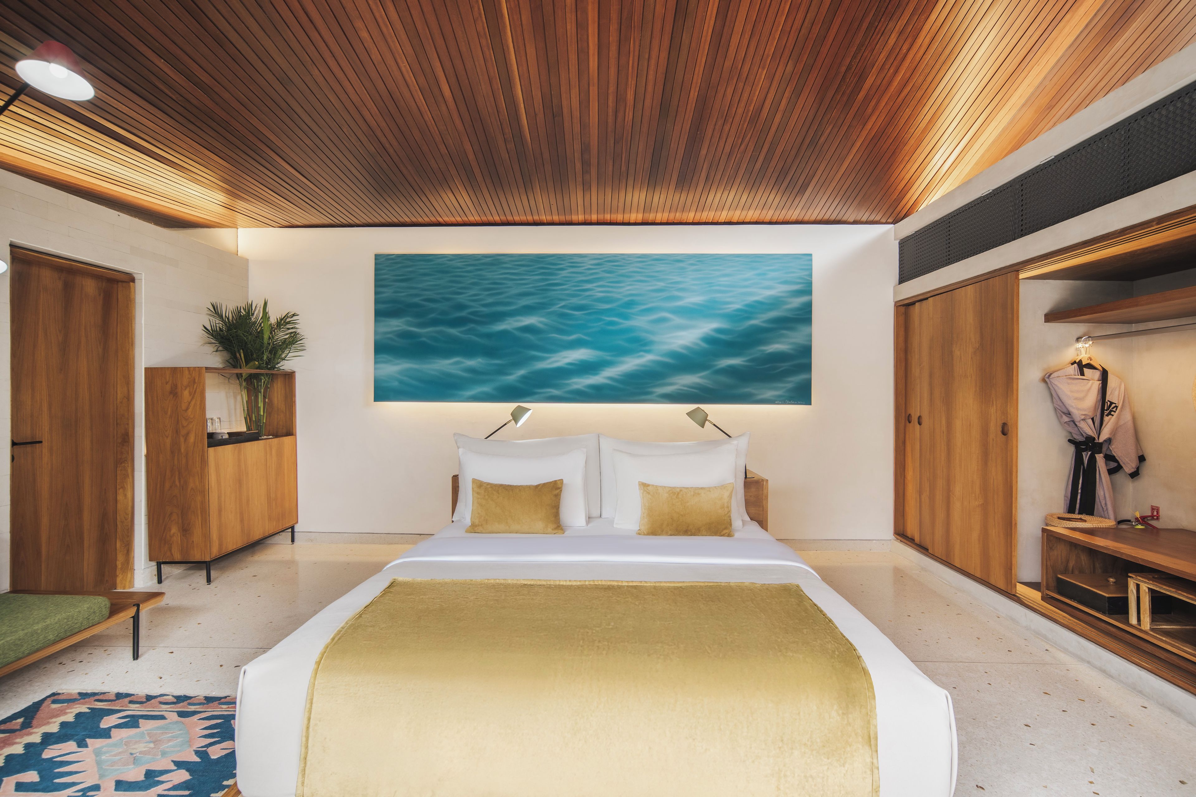 A modern bedroom with a large bed, wooden ceiling, and a wall-mounted painting.