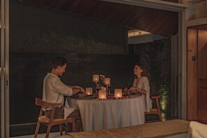 Una pareja cenando en una mesa con velas, una copa de vino y un menú.