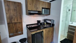 Uma cozinha compacta com armários de madeira, micro-ondas e máquina de café.